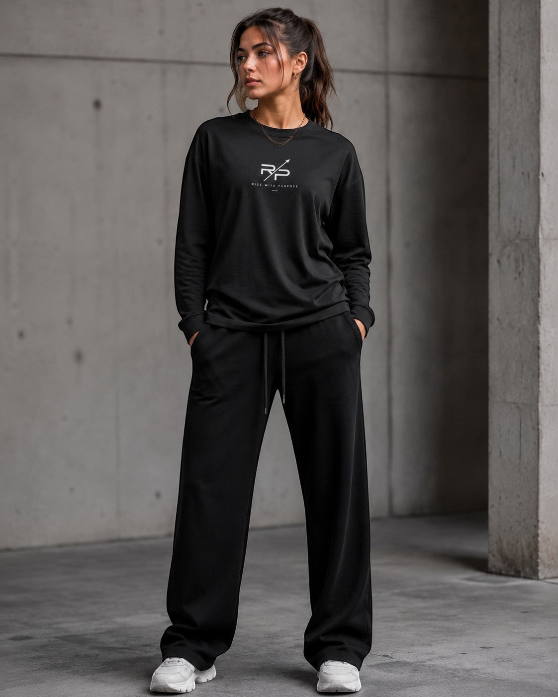 Model wearing a crew neck drop shoulder shirt with relaxed pants in a minimalist urban setting.