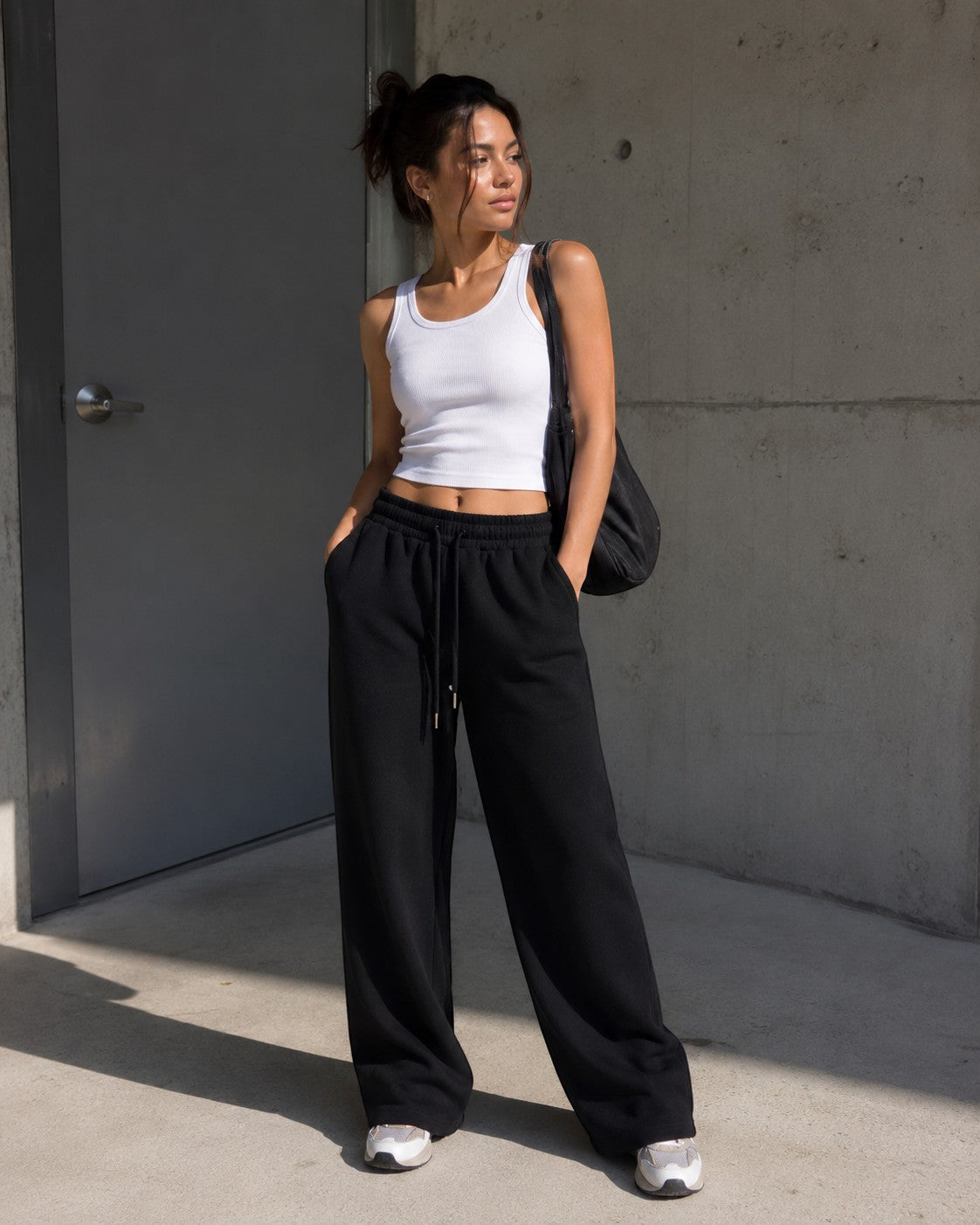 Rise With Purpose black wide leg sweatpants with elastic drawstring waist and side pockets, worn by a woman.