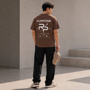 Rise With Purpose brown Sorona t-shirt with graphic print on back, worn by a man holding a cap.